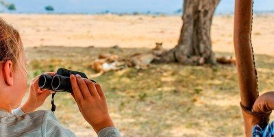 Girl on safari in Kenya with lions in the background.